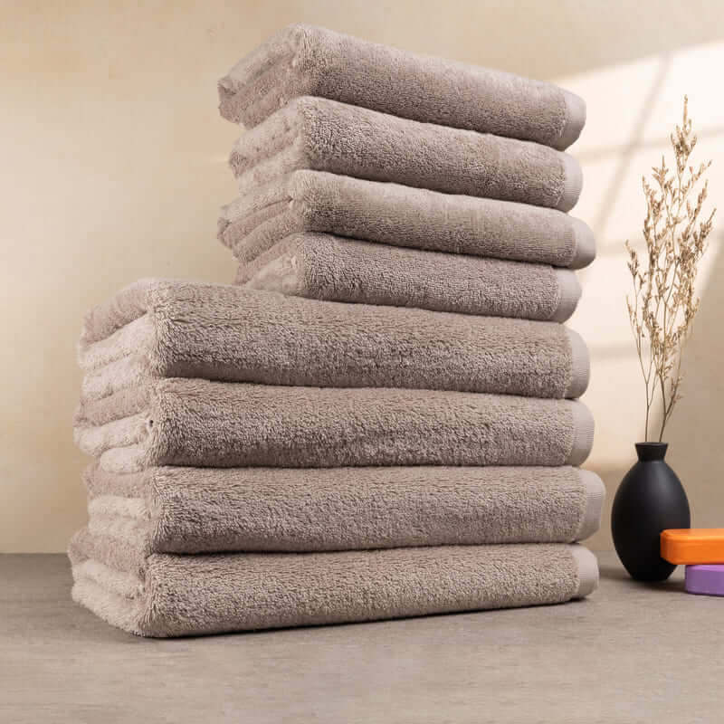 Set aus 8 Handtüchern in Cashmere-Beige, ordentlich gestapelt – ideal für luxuriöse Badeerlebnisse.